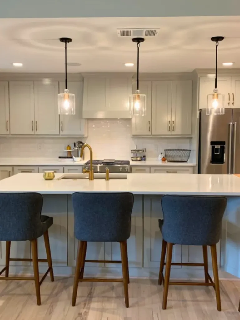 Modern kitchen with large island, pendant lighting, gold fixtures, and gray cabinetry