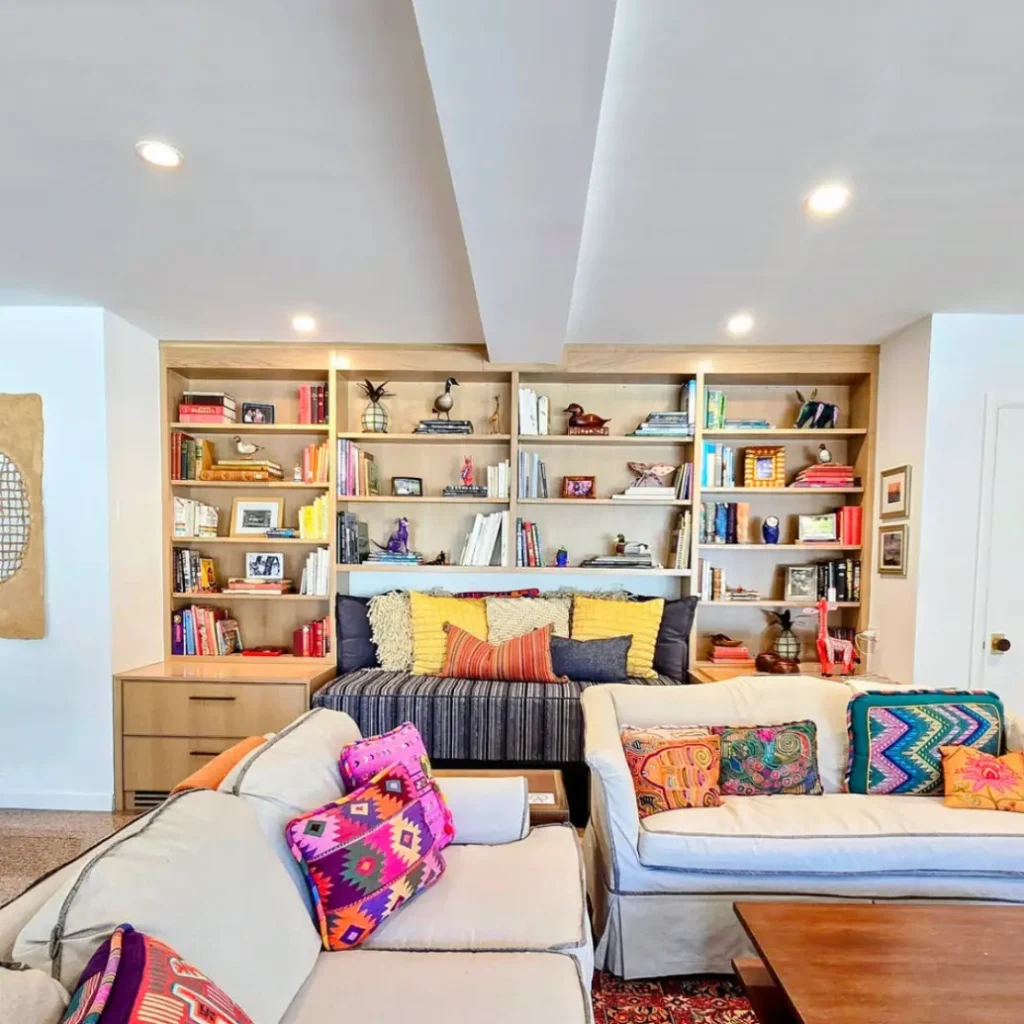 Custom built-in bookshelf and seating area with colorful decor, wood shelving, and modern living room furniture.
