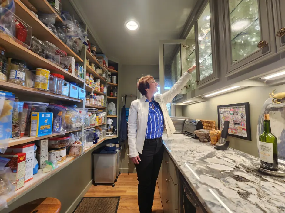 Custom pantry and prep space with open shelving, glass-front cabinetry, marble countertops, and built-in storage solutions