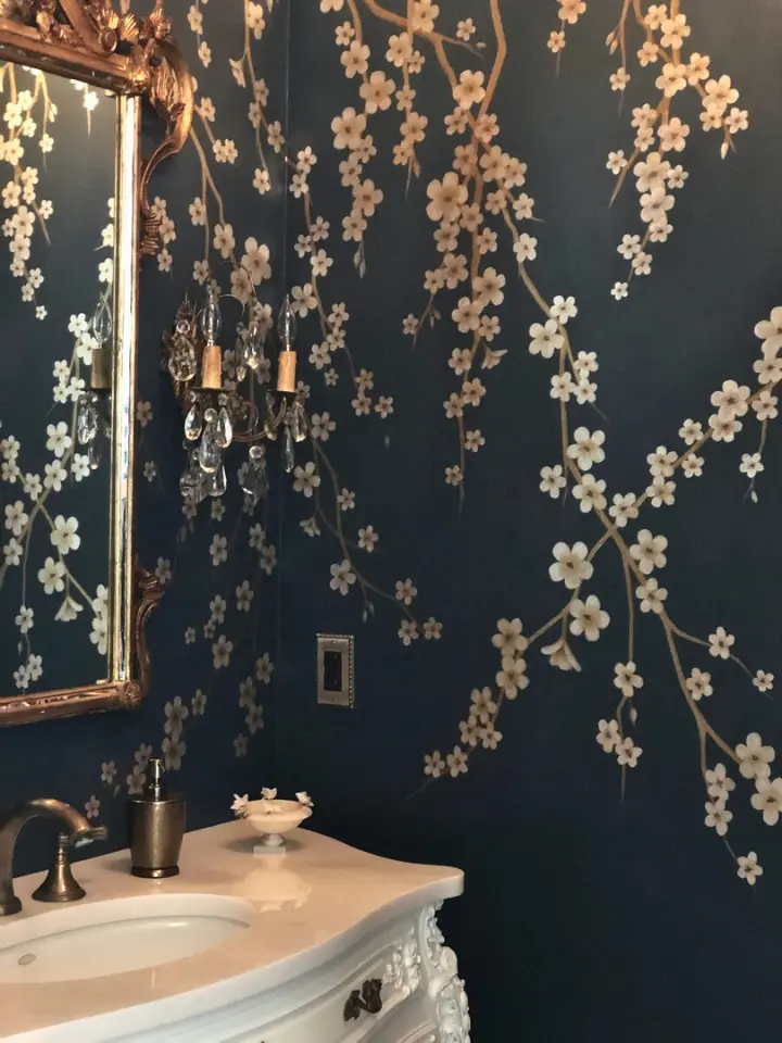 Elegant powder room with dark floral wallpaper, ornate mirror, crystal wall sconce, and vintage-style vanity.