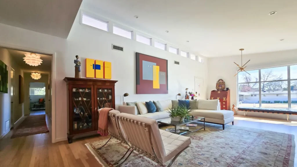 Modern living room with high ceilings, large picture windows, contemporary furniture, and abundant natural light.