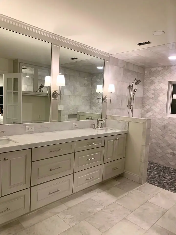 Spacious marble bathroom with double vanity, large mirrors, wall sconces, and walk-in shower.