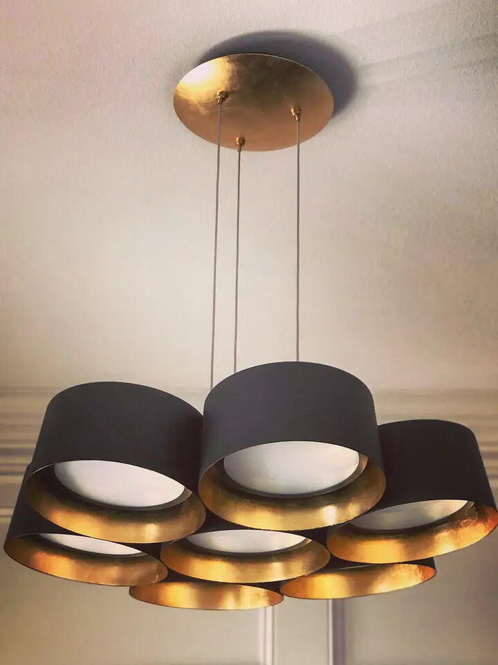 Modern black and gold circular chandelier with layered ring lights suspended from the ceiling.
