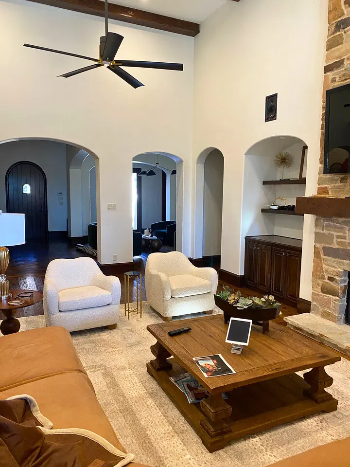 Modern living room with vaulted ceilings, stone fireplace, exposed wood beam, and arched entryways.