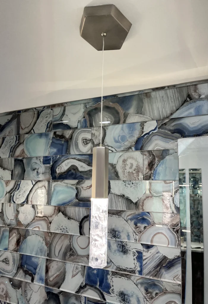 Modern pendant light installed against a blue agate-inspired feature tile wall