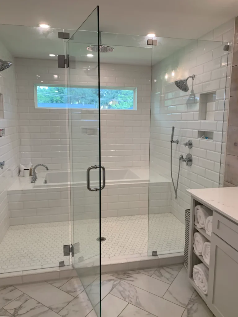 Modern walk-in shower and bathtub combination with glass enclosure, white subway tile walls, hexagon tile flooring, and chrome fixtures.