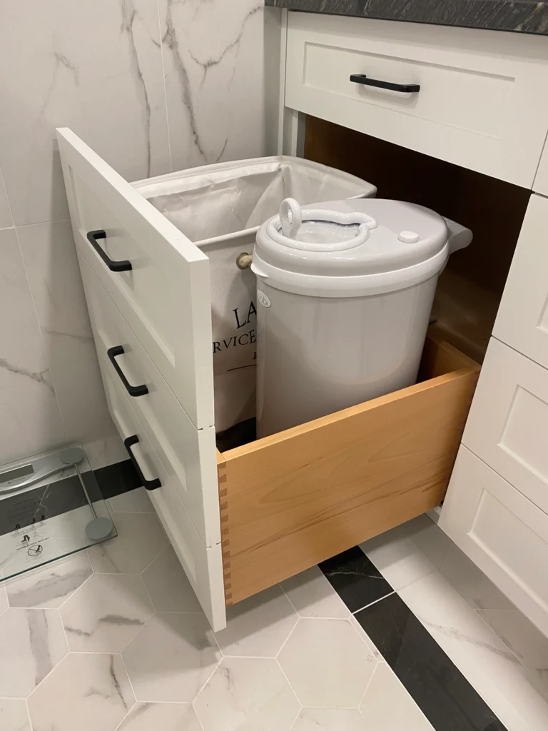 Custom bathroom pull-out storage drawer with built-in diaper disposal and concealed waste organization