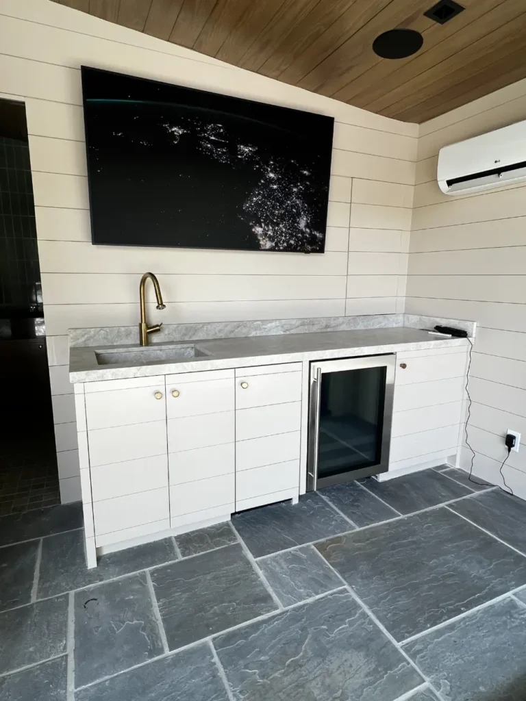 Custom laundry room with built-in cabinetry, stacked washer and dryer, utility sink, and hardwood flooring
