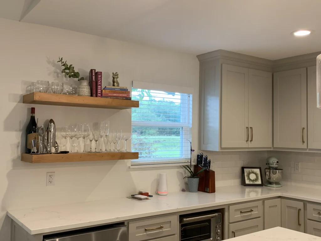Custom kitchen bar area with floating wood shelves, white cabinetry, quartz countertops, and modern finishes