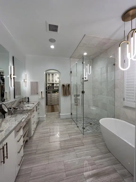 Modern luxury bathroom with freestanding tub, glass walk-in shower, dual vanity, and contemporary lighting.