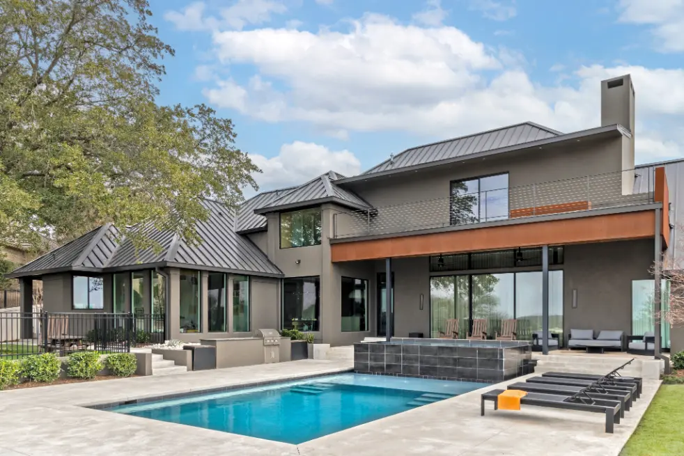 Contemporary luxury home exterior with metal roof, pool, and outdoor living area