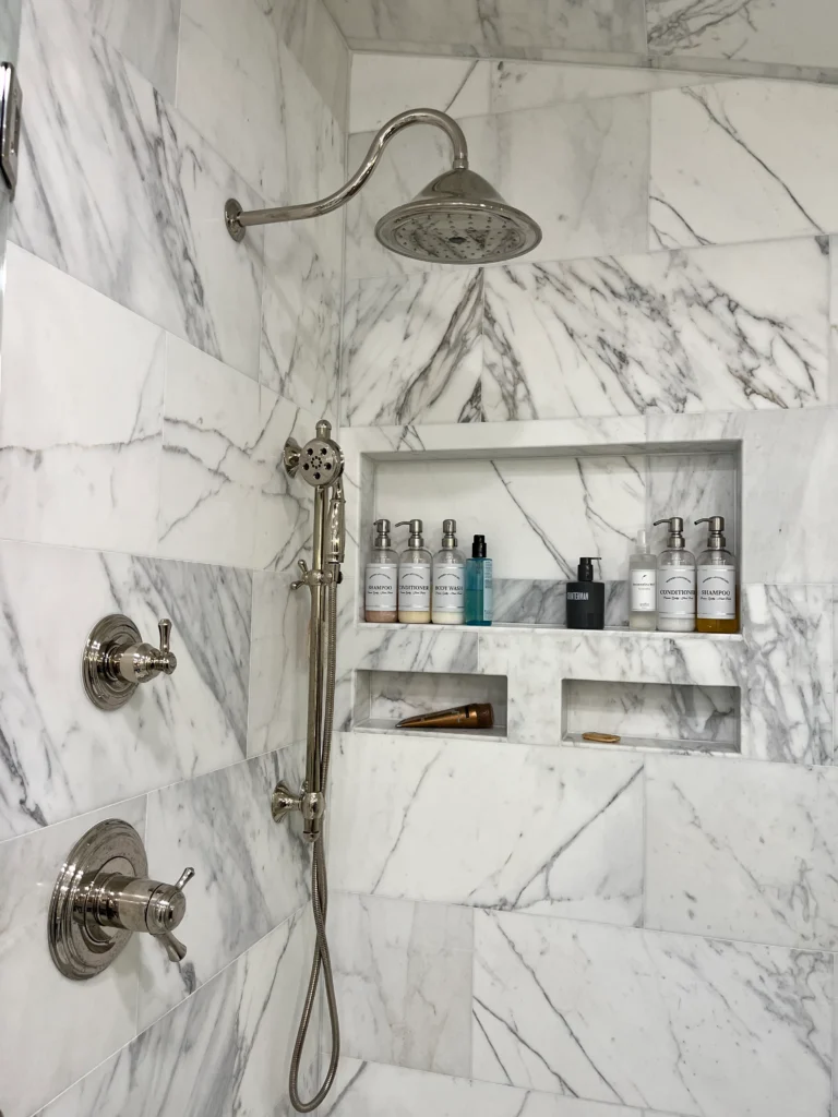 Luxury marble shower with brushed nickel fixtures, rainfall shower head, and built-in storage niches
