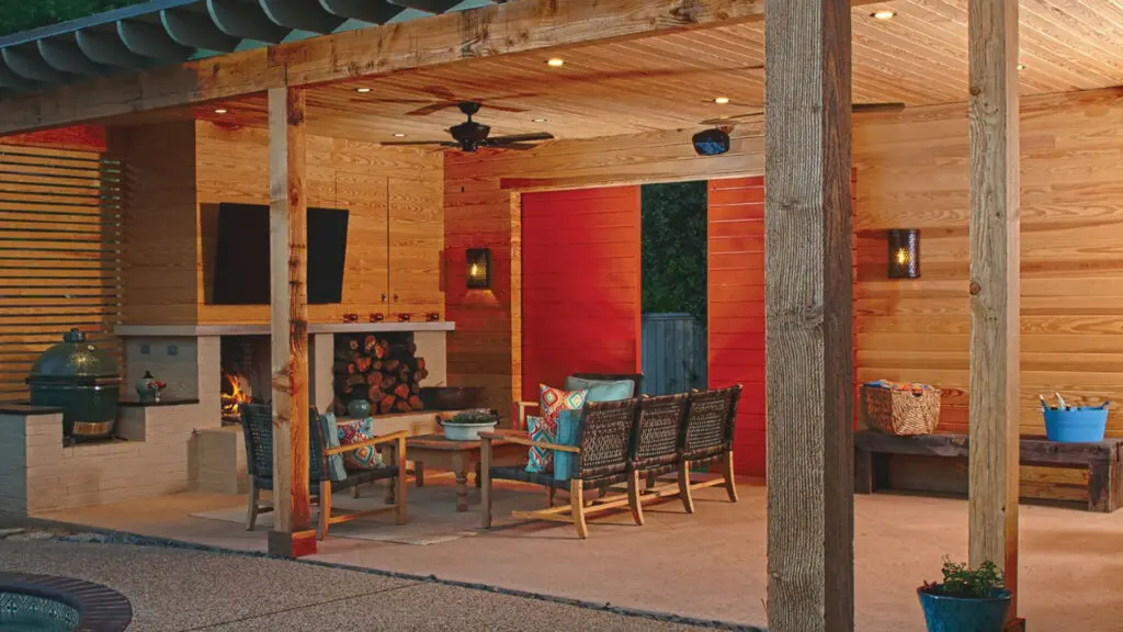 Covered outdoor living area with wood finishes, fireplace, grill station, and lounge seating