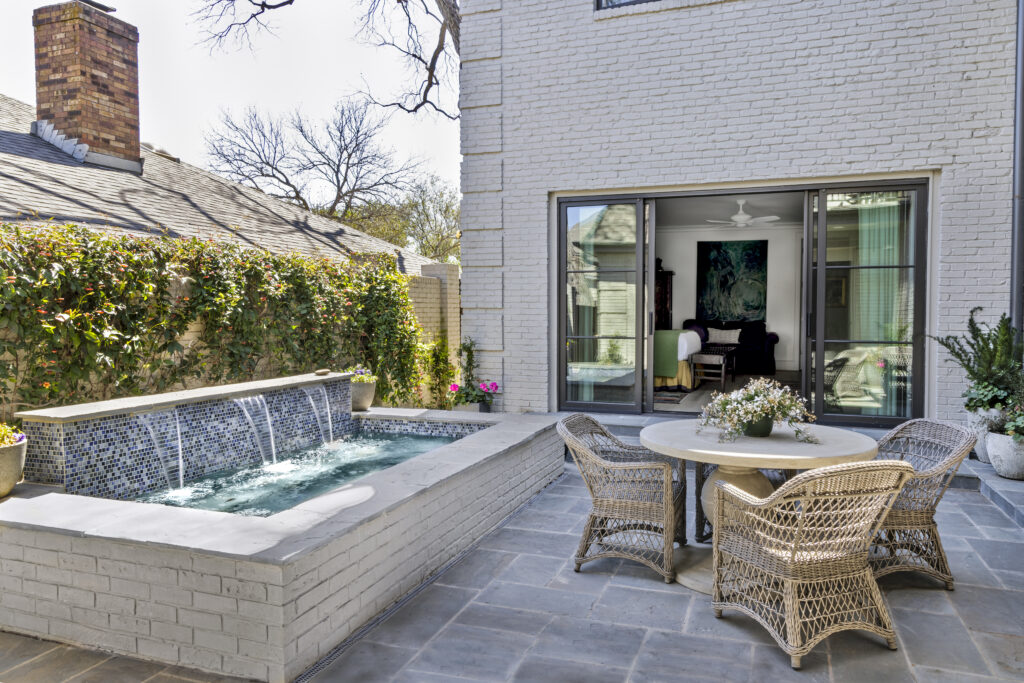 Backyard patio with spa pool, wicker seating, and large sliding glass doors leading into the home