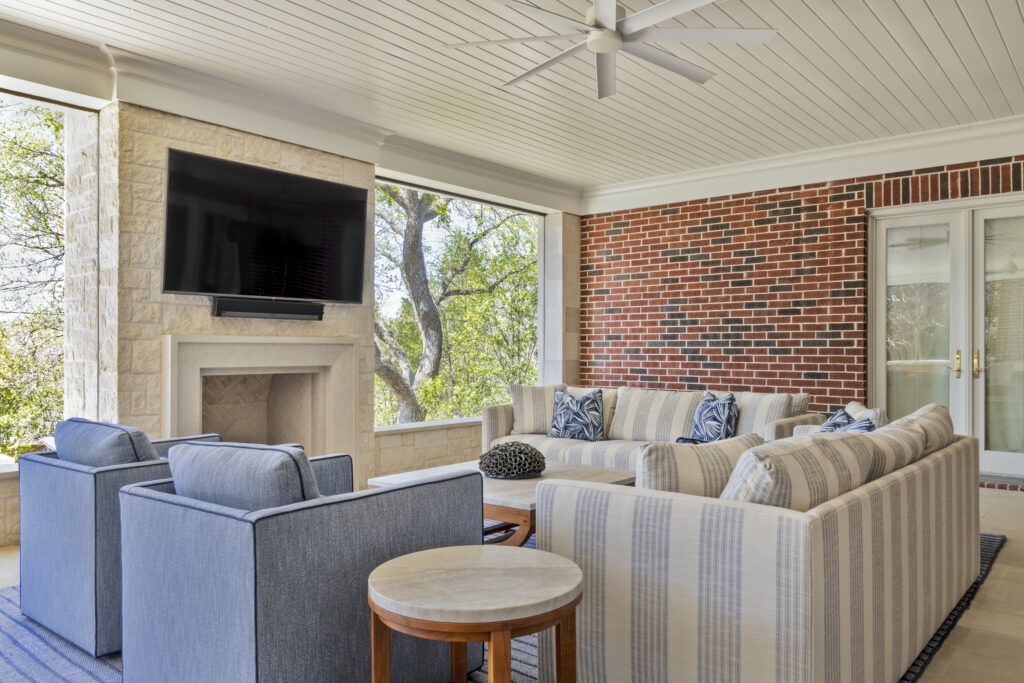 Covered outdoor living area with fireplace, mounted TV, and lounge seating at a luxury home