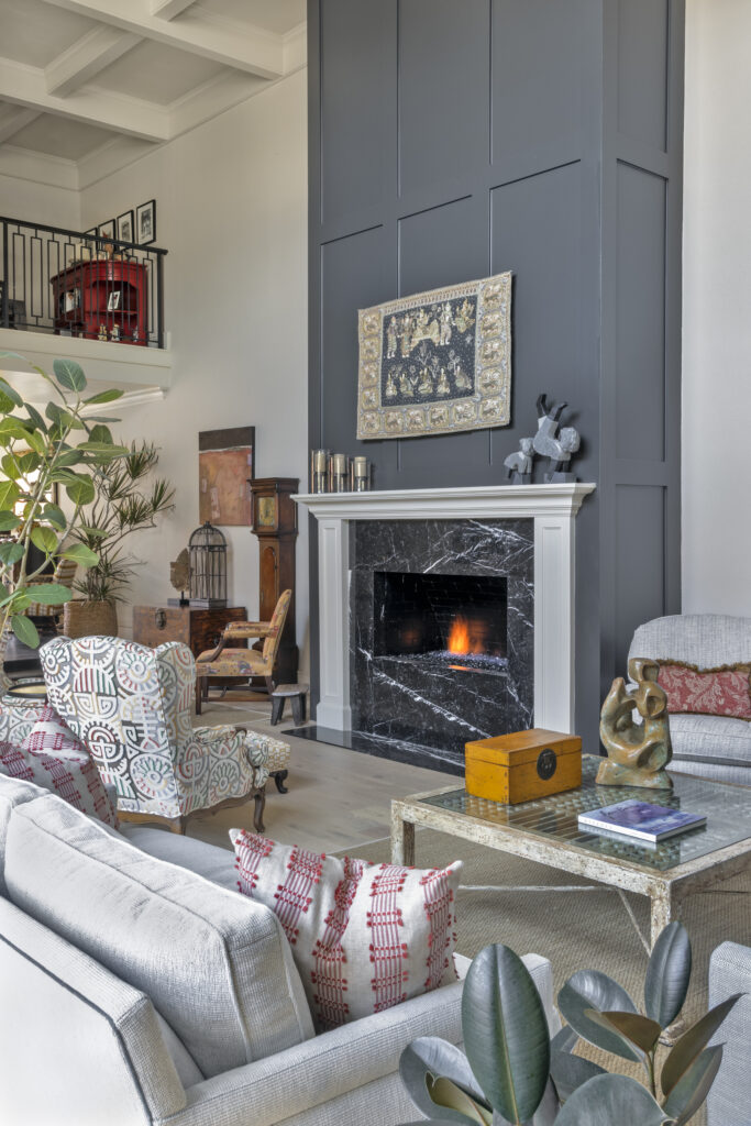 Open living room with soaring ceilings, black marble fireplace, patterned seating, and layered contemporary decor