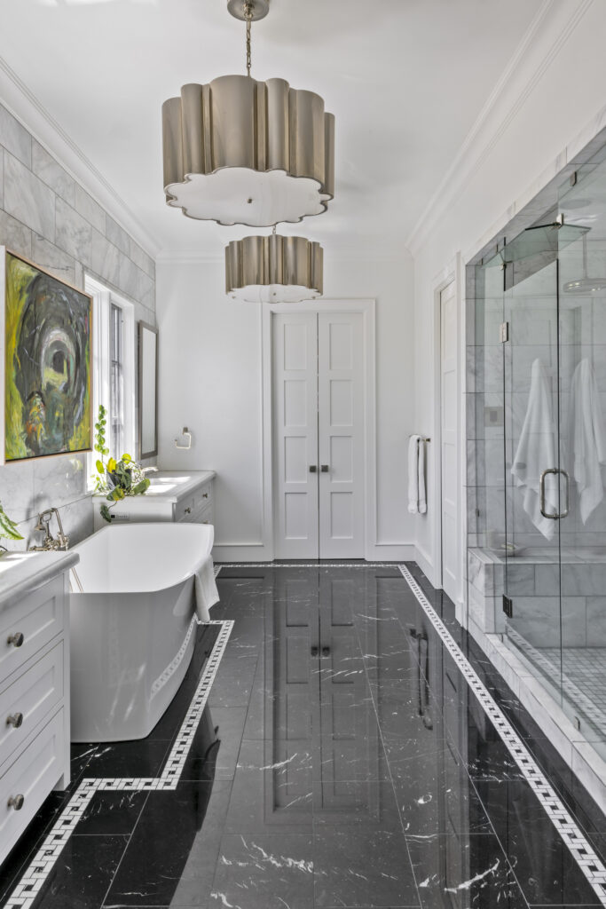 Luxury bathroom with freestanding soaking tub, black marble flooring, white vanity, and modern pendant lighting