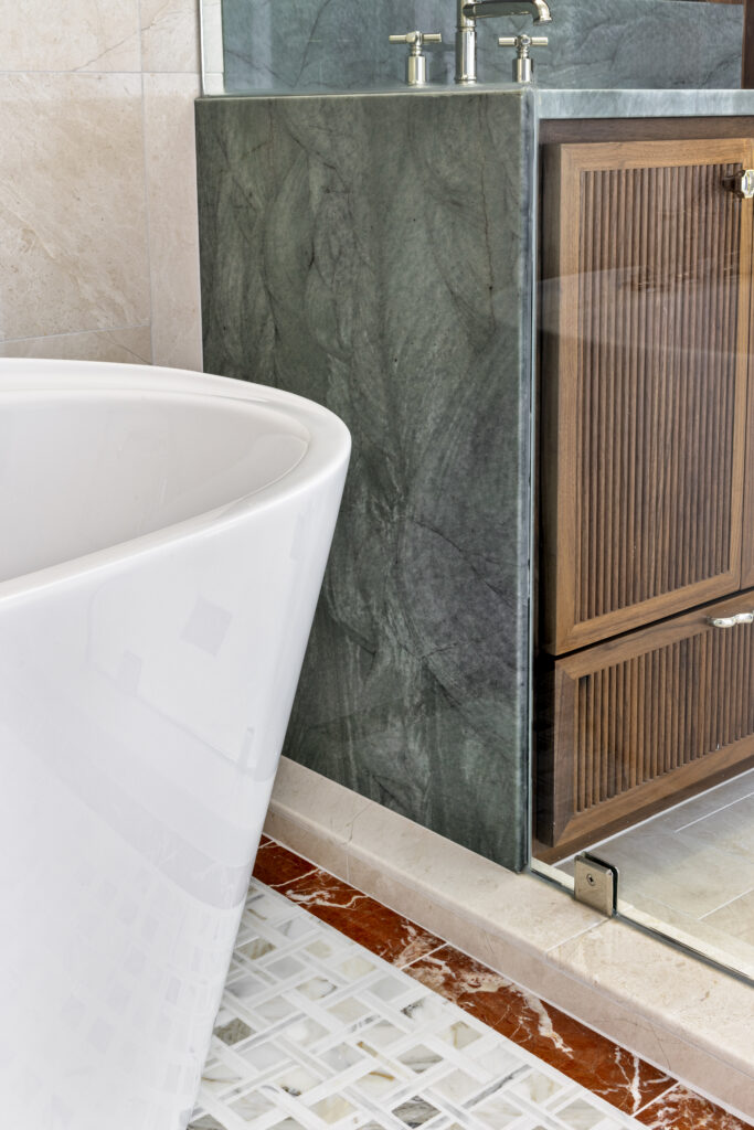 Luxury bathroom vanity with dark stone surround, wood cabinetry, and freestanding soaking tub detail