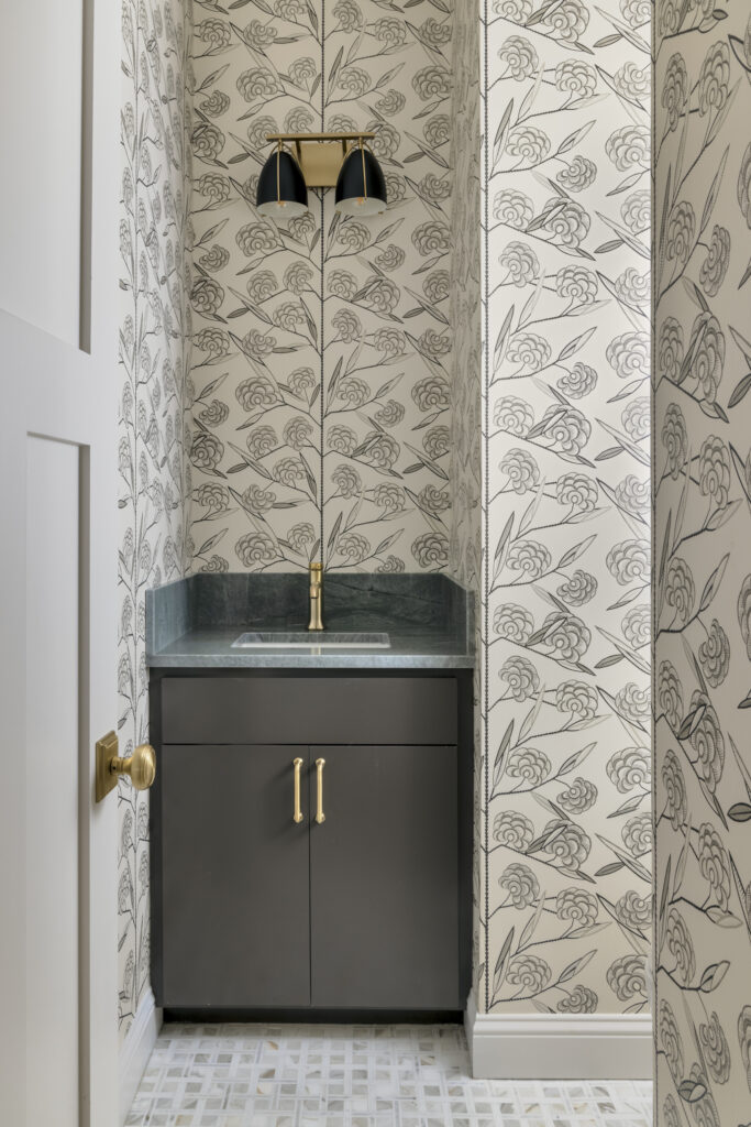 Powder bathroom with floral wallpaper and dark vanity cabinetry in a luxury home