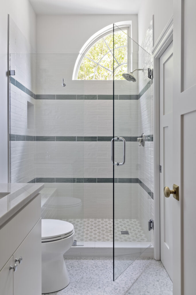Modern bathroom with glass walk-in shower and arched window in a luxury home