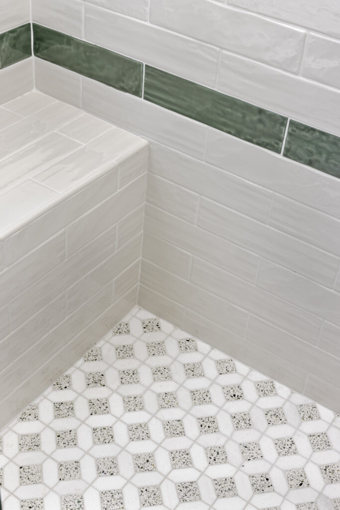 Bathroom tile detail with green accent trim and patterned hexagon flooring