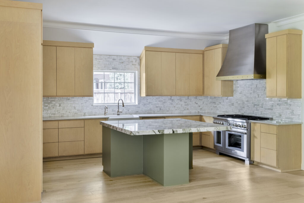Spacious modern kitchen with light wood cabinetry, marble island, stainless steel range, and custom metal vent hood