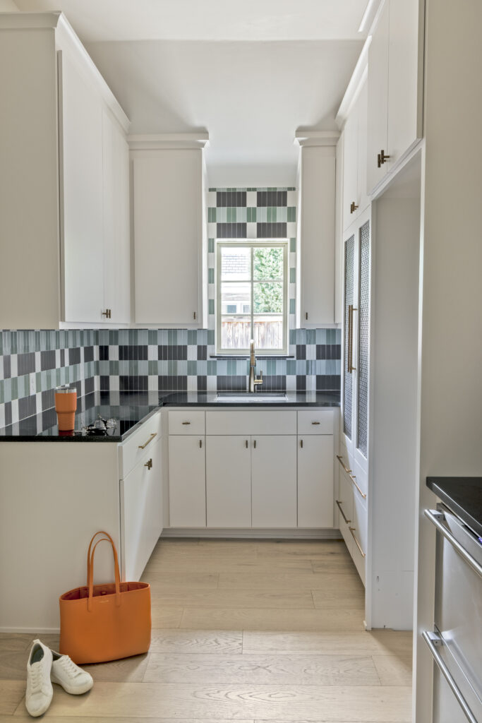 Bright custom kitchen with white cabinetry, geometric tile backsplash, and black countertops