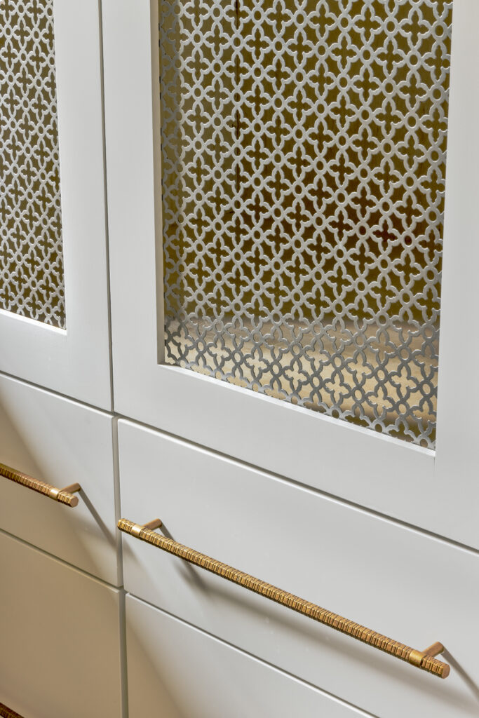 Close-up of custom cabinetry with decorative metal mesh inserts and brass hardware detail