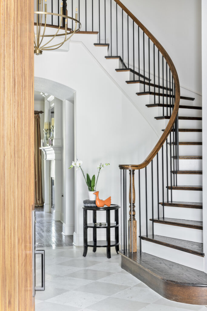 Curved wood staircase with dark railings in a luxury home entryway
