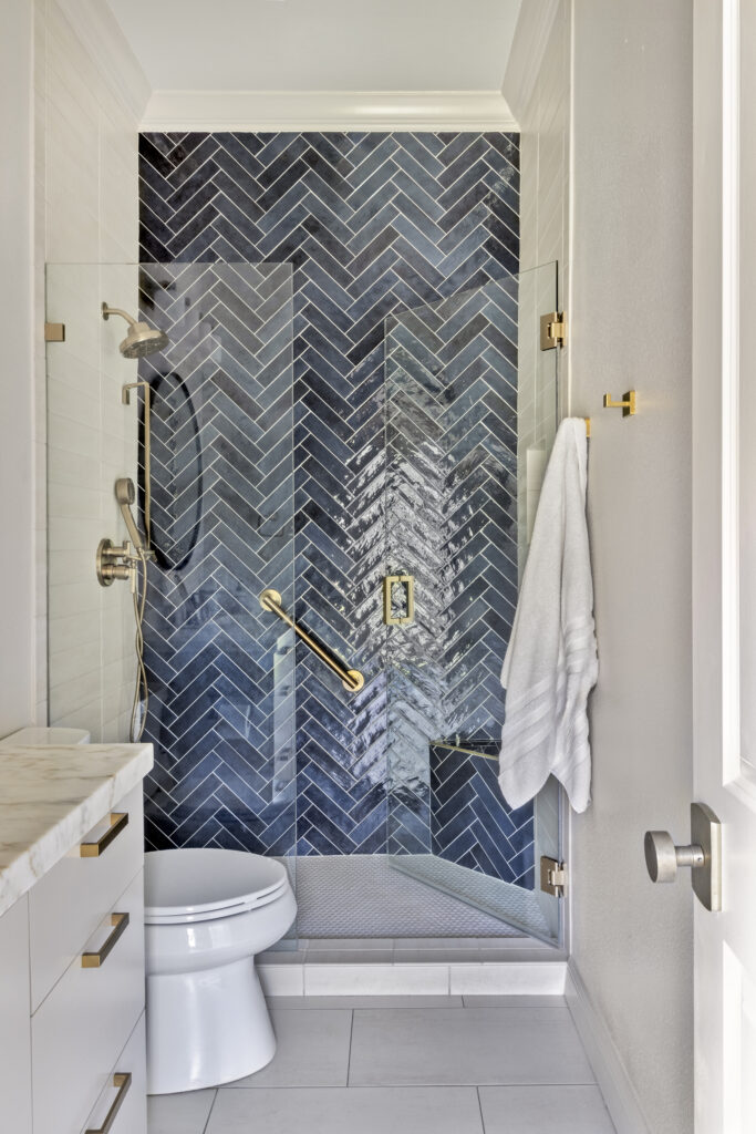 Modern bathroom with blue herringbone tile shower and glass enclosure in a luxury home