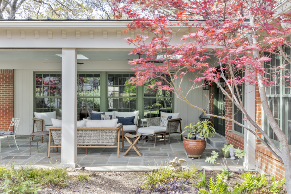 Covered outdoor patio seating area with landscaped garden at a luxury home