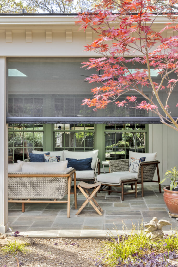 Covered outdoor patio seating area with landscaped garden at a luxury home