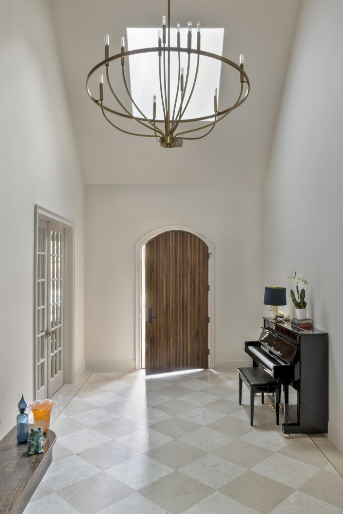 Luxury home entry hallway with vaulted ceiling, chandelier, and wood front door