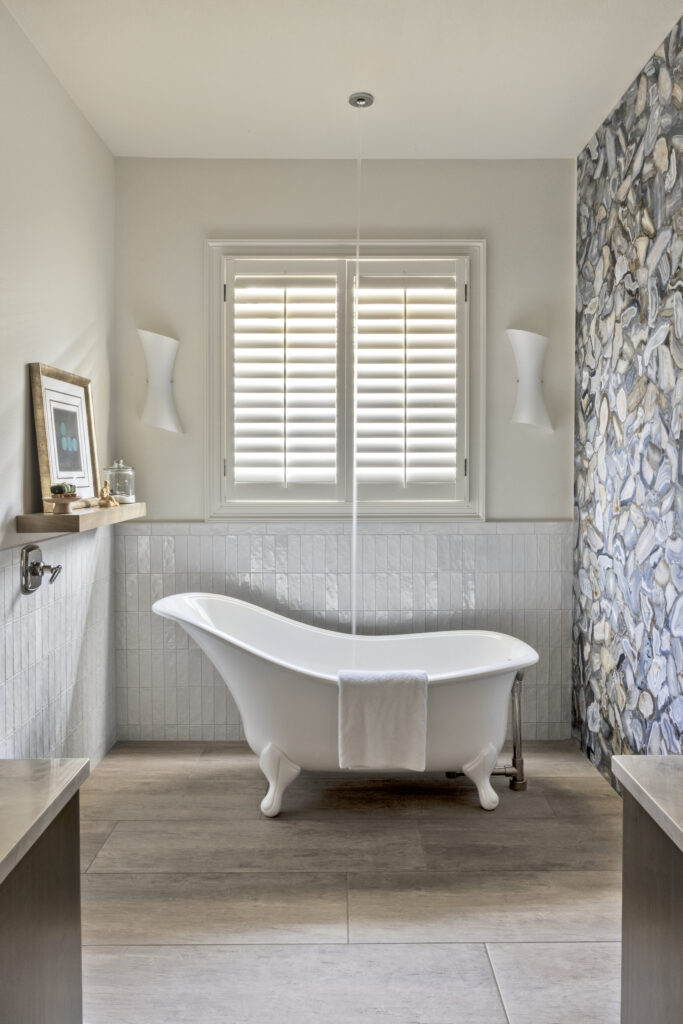 Freestanding soaking tub with patterned accent wall in a luxury bathroom