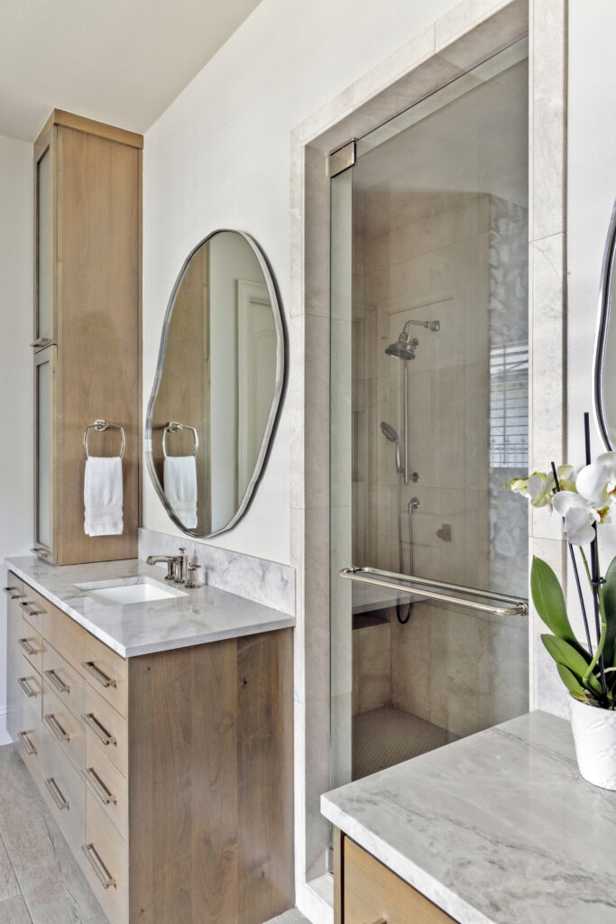 Modern bathroom vanity with wood cabinetry and glass walk-in shower in a luxury home