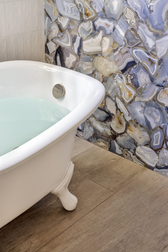 Freestanding bathtub beside a blue agate-style accent wall in a luxury bathroom
